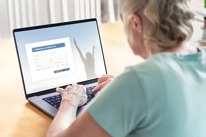 An elderly woman books an appointment on her laptop using an online form